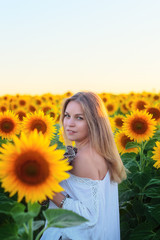 Portrait of a beautiful slender blonde woman in a field with sunflowers, freedom and femininity