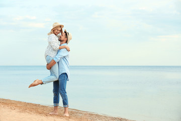 Fototapeta na wymiar Happy romantic couple spending time together on beach, space for text
