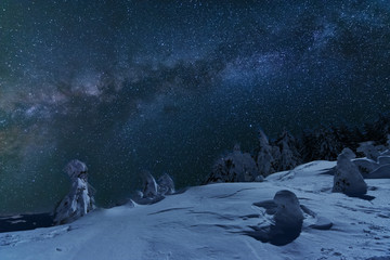 Fototapeta premium Fairytale landscapes of the winter Carpathian Mountains with a charming milky way in the sky tourist tents and snowy houses in the valleys