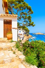 Photo sur Plexiglas Europe méditerranéenne Porte en bois d& 39 une maison blanche décorée de fleurs et vue sur la plage dans le village de pêcheurs de Sa Tuna, Costa Brava, Catalogne, Espagne