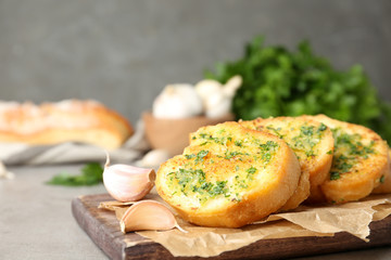 Slices of toasted bread with garlic and herbs on light table against grey background