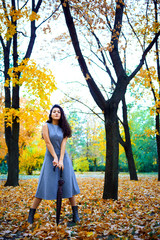 woman posing with umbrella and autumn leaves in city park, outdoor portrait