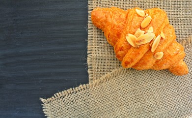 Fototapeta na wymiar Almond Croissant on a sackcloth background