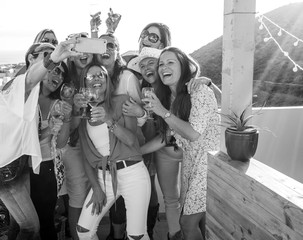 Laughter and smiles for a selfie. A group of nine happy females people toast with a glass of wine to their friendship. Horizon over water