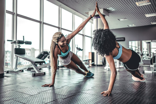 Sporty women giving high five to each other while working out together at gym.