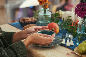 Close up female hands holding cup of tea on the background of festive autumn table