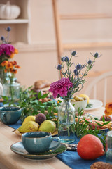 Flower in vase, pumpkin, pear, green, spruce branch and cup of tea on the autumn served table