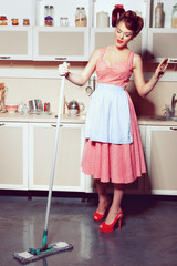 Young beautiful housewife washes the floor in the kitchen.