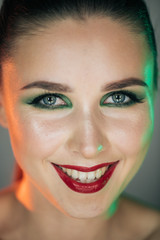 A stunning make-up on the face of a beautiful young girl, beauty makeup, oil on her face and sparkly green with priority red