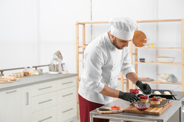 Male pastry chef preparing desserts at table in kitchen. Space for text