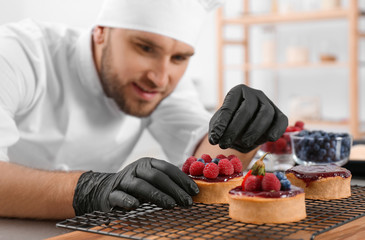 Male pastry chef preparing desserts at table in kitchen