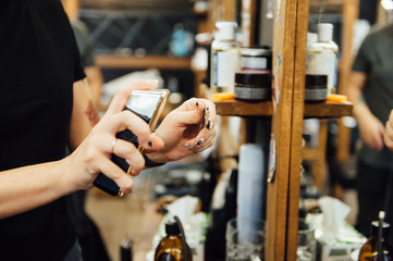 The hands of young barber making haircut to attractive man in barbershop