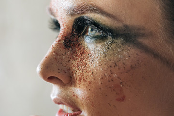 A stunning make-up on the face of a beautiful young girl, beauty makeup, oil on her face and sparkly green with priority red