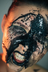 Obraz premium Stunning makeup on the face of a beautiful young girl, black drops of makeup, oil on the face and sparkles