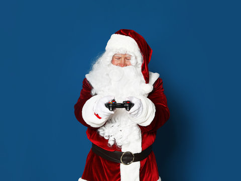 Authentic Santa Claus with game controller on blue background. Space for text