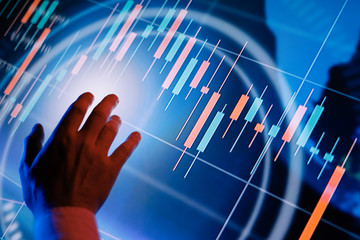 Businessman is pointing on a hi technology futuristic digital screen with financial analytics