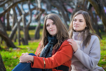 Fototapeta premium Two pretty girlfriends are sitting on lawn in park
