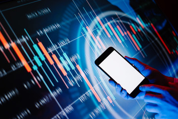 Male hands with smartphone in front of a digital display with financial information. Blank empty screen. Mock up