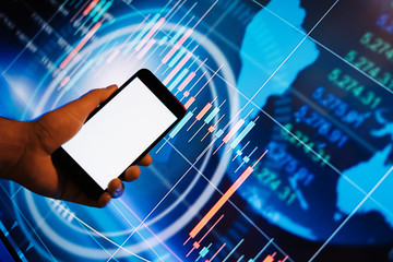 Male hands with smartphone in front of a digital display with financial information. Blank empty screen. Mock up