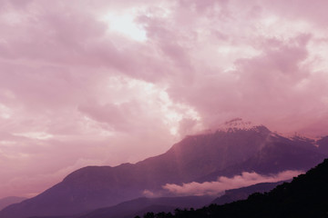The outlines of mountains and hills through the evening atmospheric fog. A picturesque place for trekking. Fantasy postcard.
