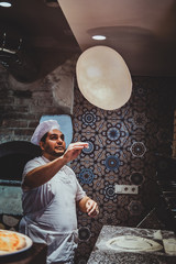 Italian chef is tossing pastry for pizza at the kitchen while cooking.