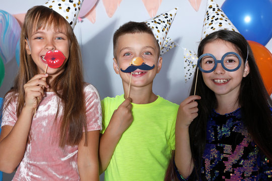 Happy children with photo booth props at birthday party indoors