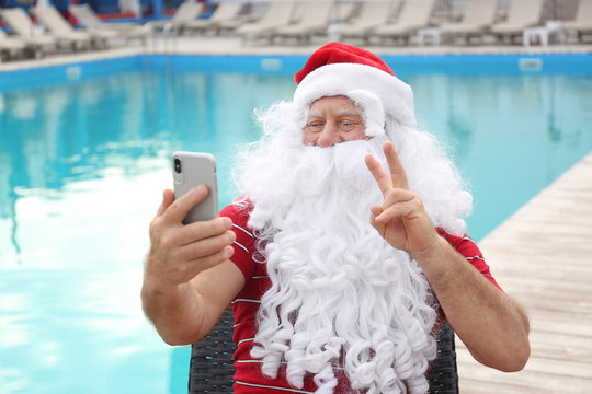 Authentic Santa Claus taking selfie near swimming pool outdoors