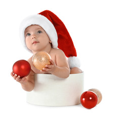Cute little baby wearing Santa hat sitting in box with Christmas decorations on white background