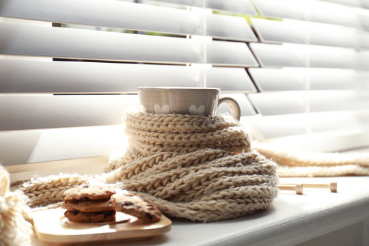 Cup of hot winter drink and cookies on windowsill indoors