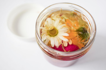 glass bottle oil based on various medicinal herbs and flowers, cosmetic oil for skin care on white background