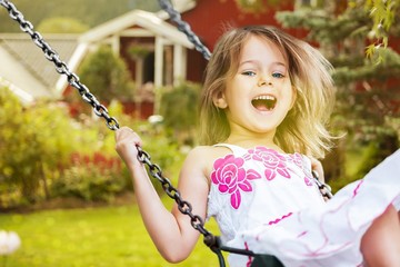 Little child blond girl having fun on a swing