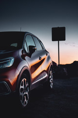 A car parked at the beach in beautiful colorful summer sunset light with reflection in the sculptural body. Vacation trip on a road trip. Lagos, Faro, Portim&atilde;o, Algarve coast in Portugal, Atlantic