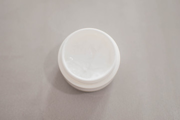 A beauty cream on a plastic container on a gray background