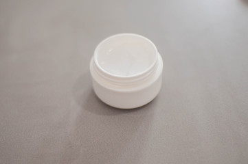 A beauty cream on a plastic container on a gray background