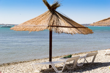 Vacation background. Two loungers with towel on one of them and umbrella on a beach. Sunny day.