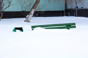 Wooden bench in the garden of the house in winter under the snow, inaction of snow blowers in the...