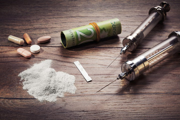 Fototapeta na wymiar Vintage syringes, cocaine, pills and rolled dollar bills on wooden table