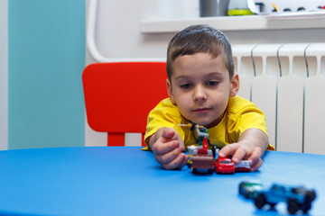 Little boy in yellow t-shirt playing with cars and toys at home, indoor