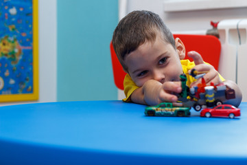 Little boy in yellow t-shirt playing with cars and toys at home, indoor