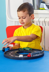 Little boy in yellow t-shirt playing with cars and toys at home, indoor