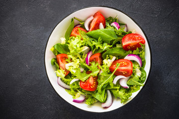 Fototapeta na wymiar Green salad from leaves and tomatoes.