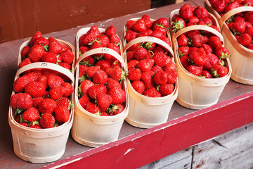 Fresh strawberries in the basket on the wooden stall of a farmer's market
