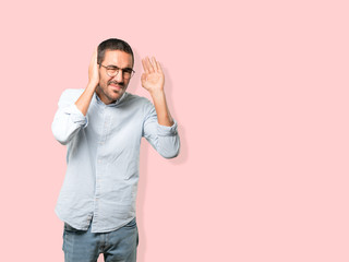 Concentrated young man making a gesture of trying to hear something