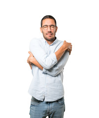 Concerned young man making a gesture of being cold
