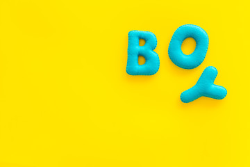 Boy word as decoration for baby shower on yellow background top view frame copy space
