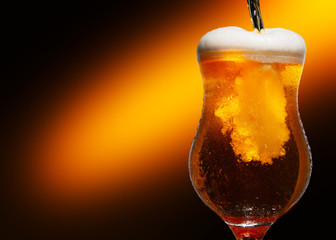 Glass of cold craft light beer on dark background..