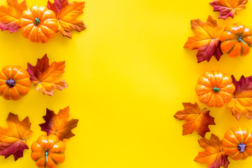 Autumn frame with colorful leaves and pumpkins on yellow background top view space for text