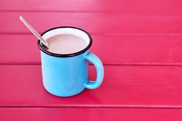 Vintage coffee cup filled with coffee and cream on pink wooden table