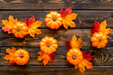 Autumn composition. Pattern with red and orange leaves and pumpkins on dark wooden background top view