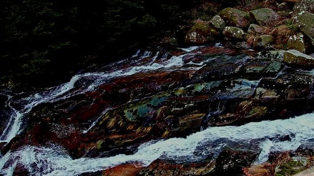 Bergbach, der &uuml;ber rotbraune Steine rasch flie&szlig;t